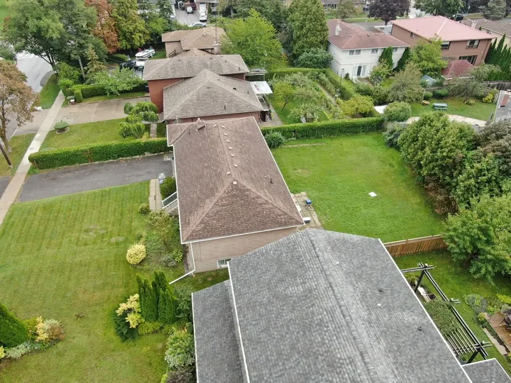 Oblique aerial photograph of residential rooftops, lawns and gardens.